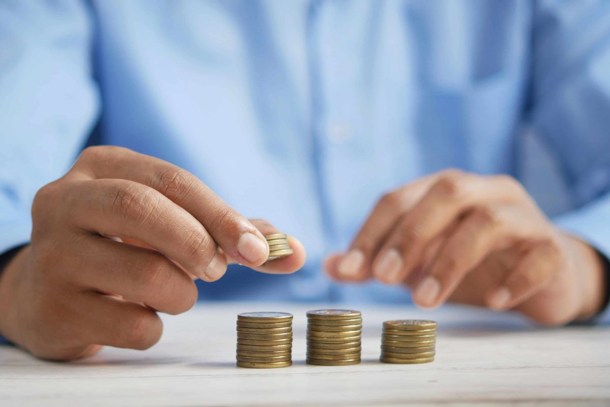 Hands stacking coins into three columns on a desk
