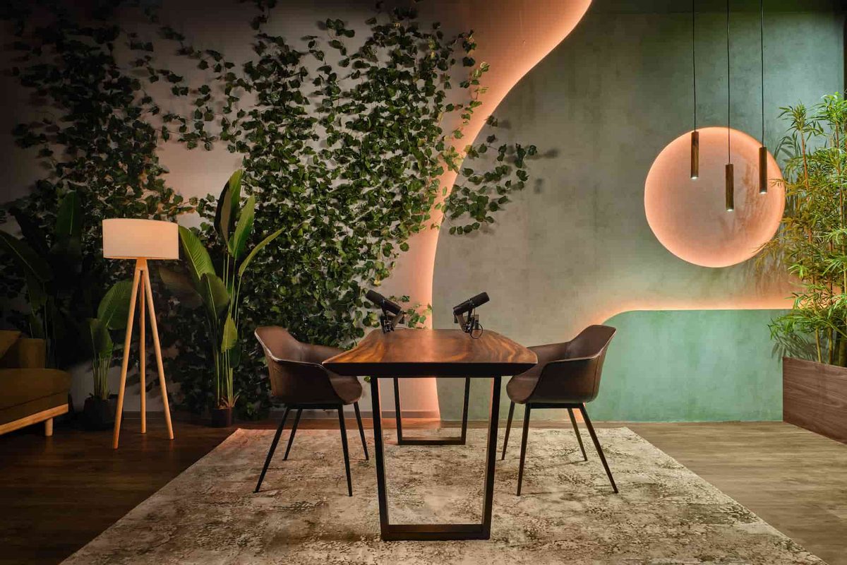A green-walled studio with a wooden table, chairs, and plants
