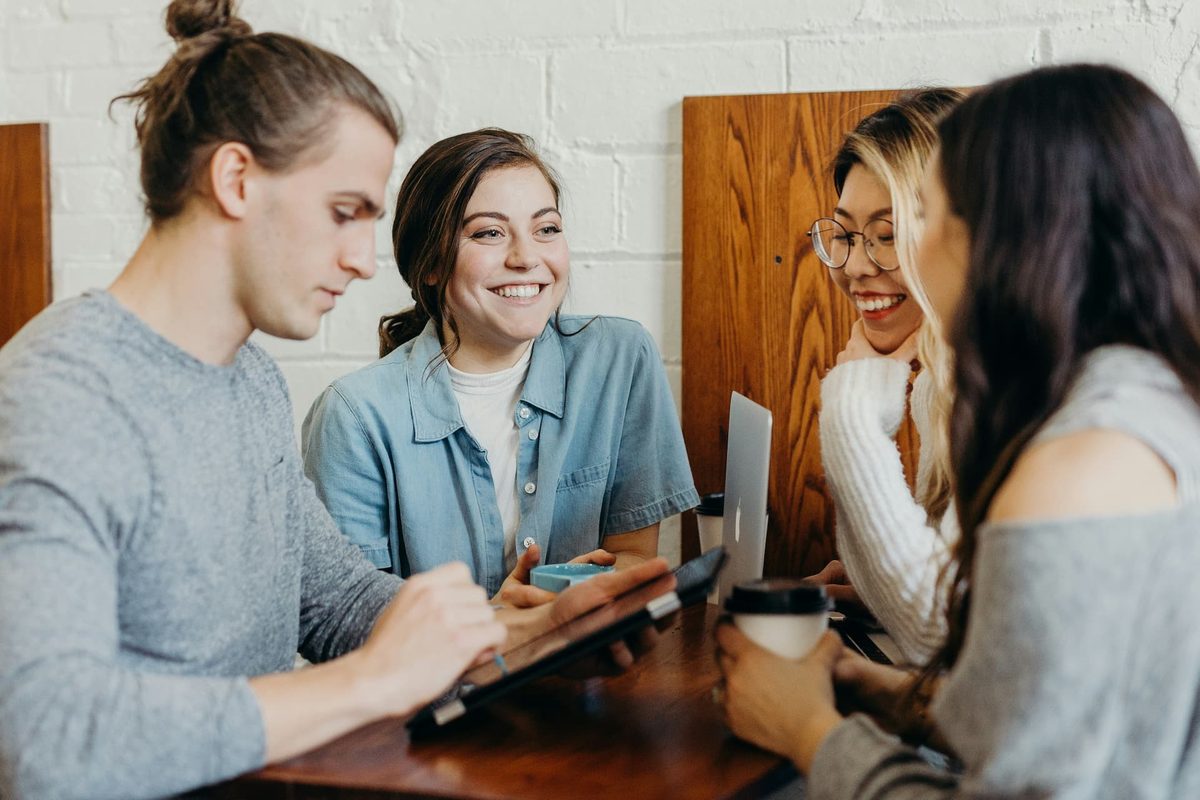 Four people talking over a tablet at a table