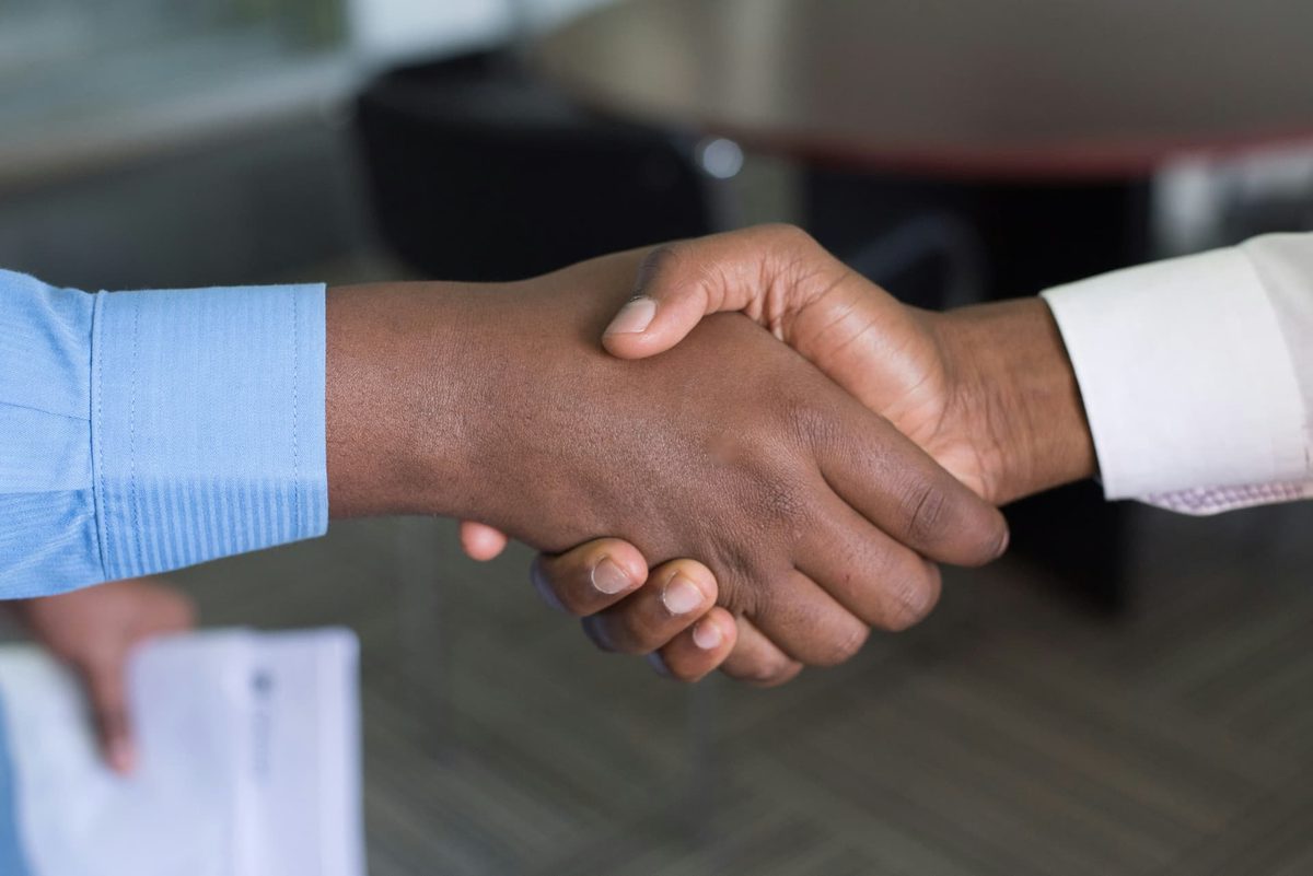 Two people shaking hands over a desk
