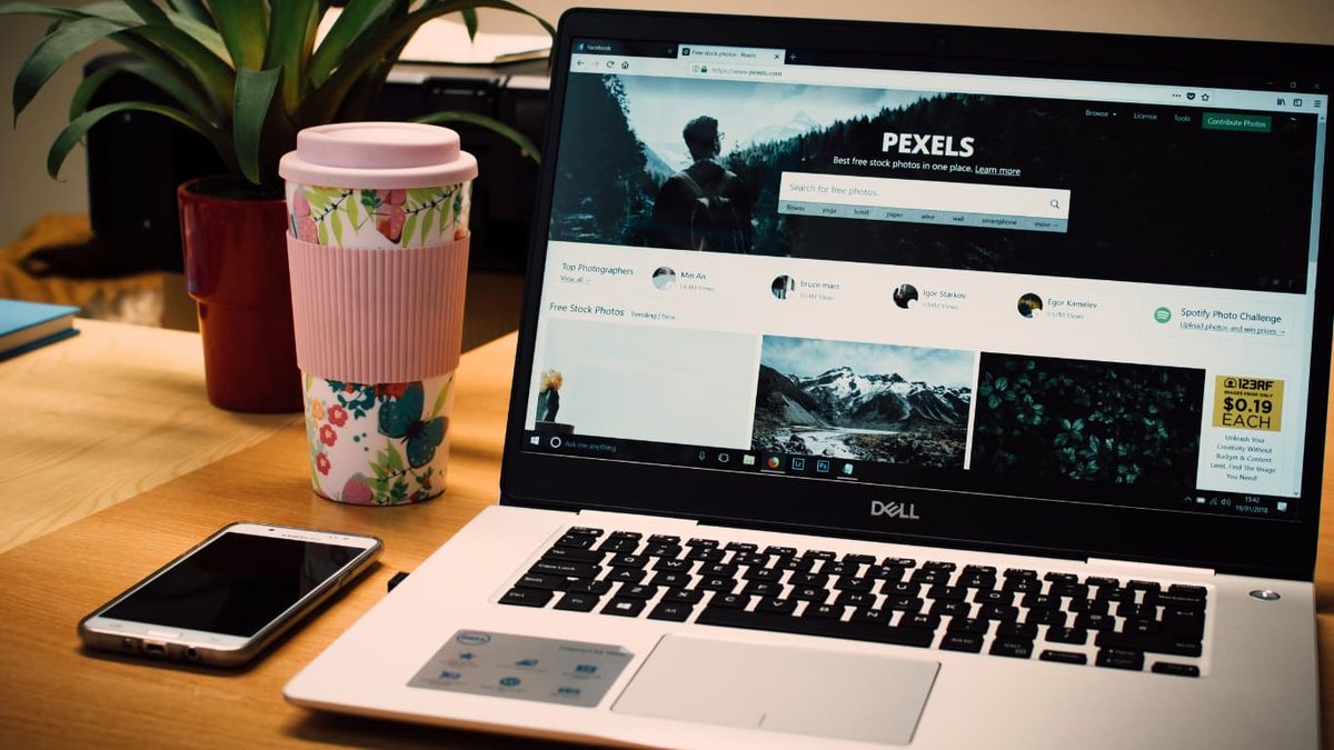 A laptop and phone on a desk, with a photo library open in the browser