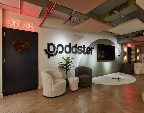 A studio reception with the Poddster logo and an on-air sign