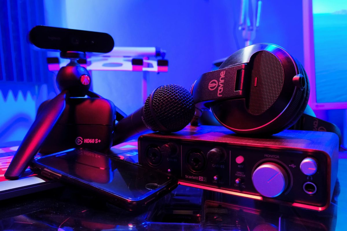 A microphone, headphones and an audio interface lit in red and blue