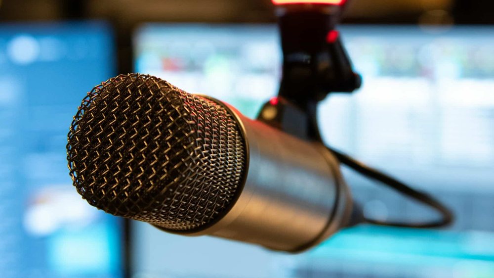 A close-up of a microphone in front of a bright studio backdrop