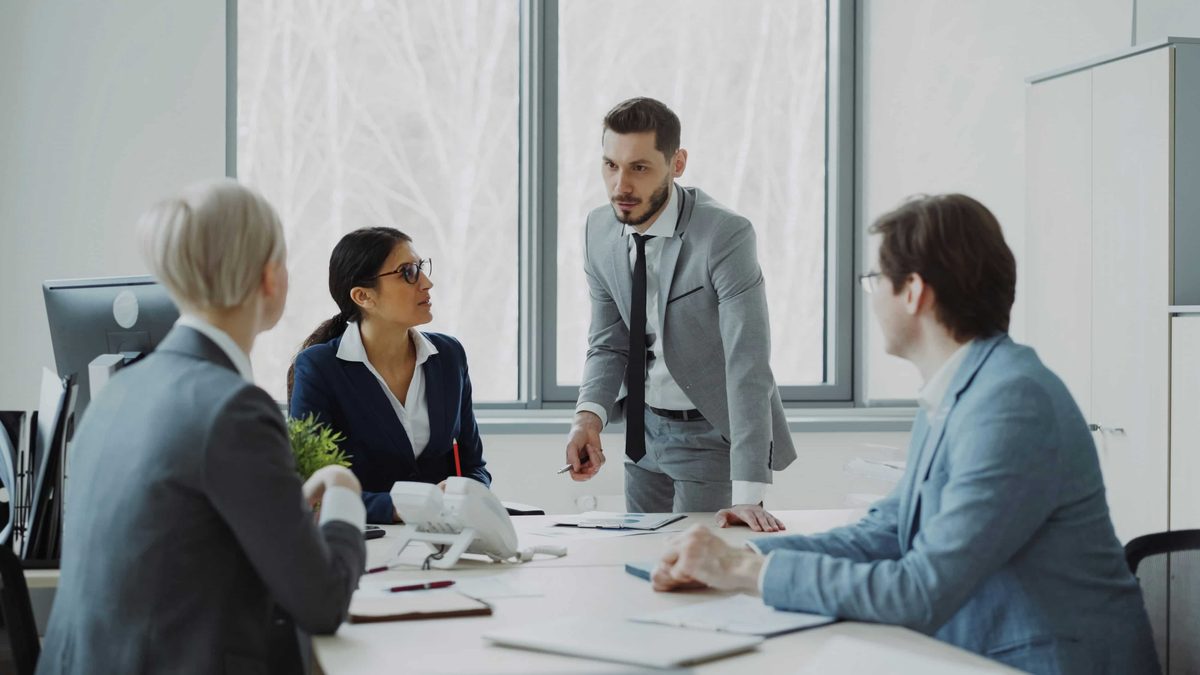 Four colleagues talking around a meeting table in a bright office