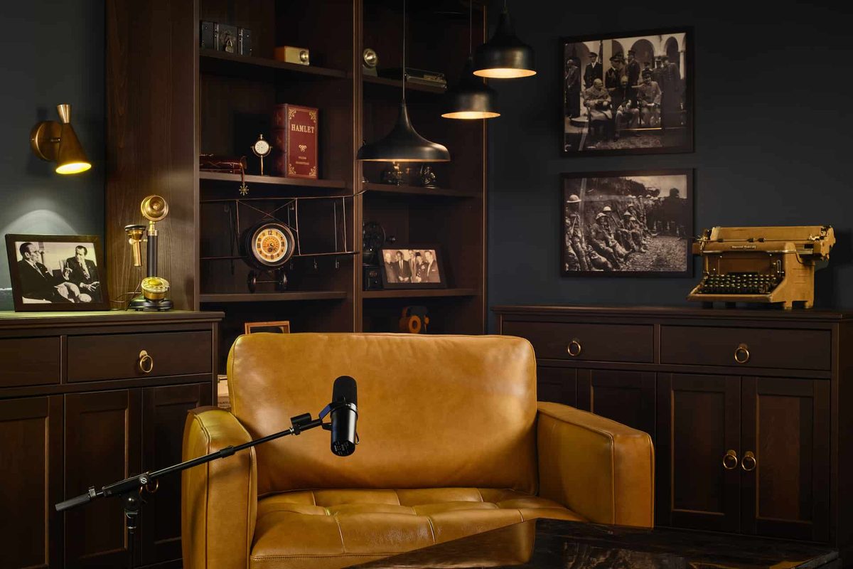 A leather armchair and microphone in a warmly lit, book-lined studio