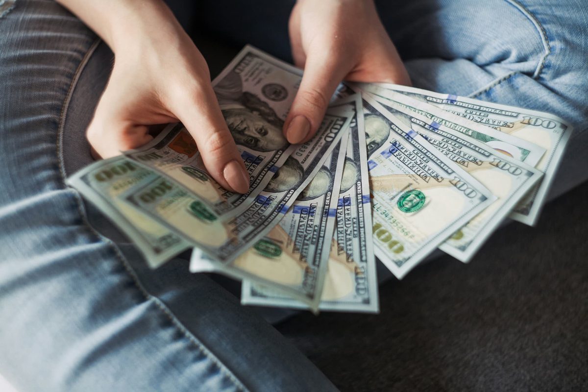 Hands fanning out a stack of dollar bills