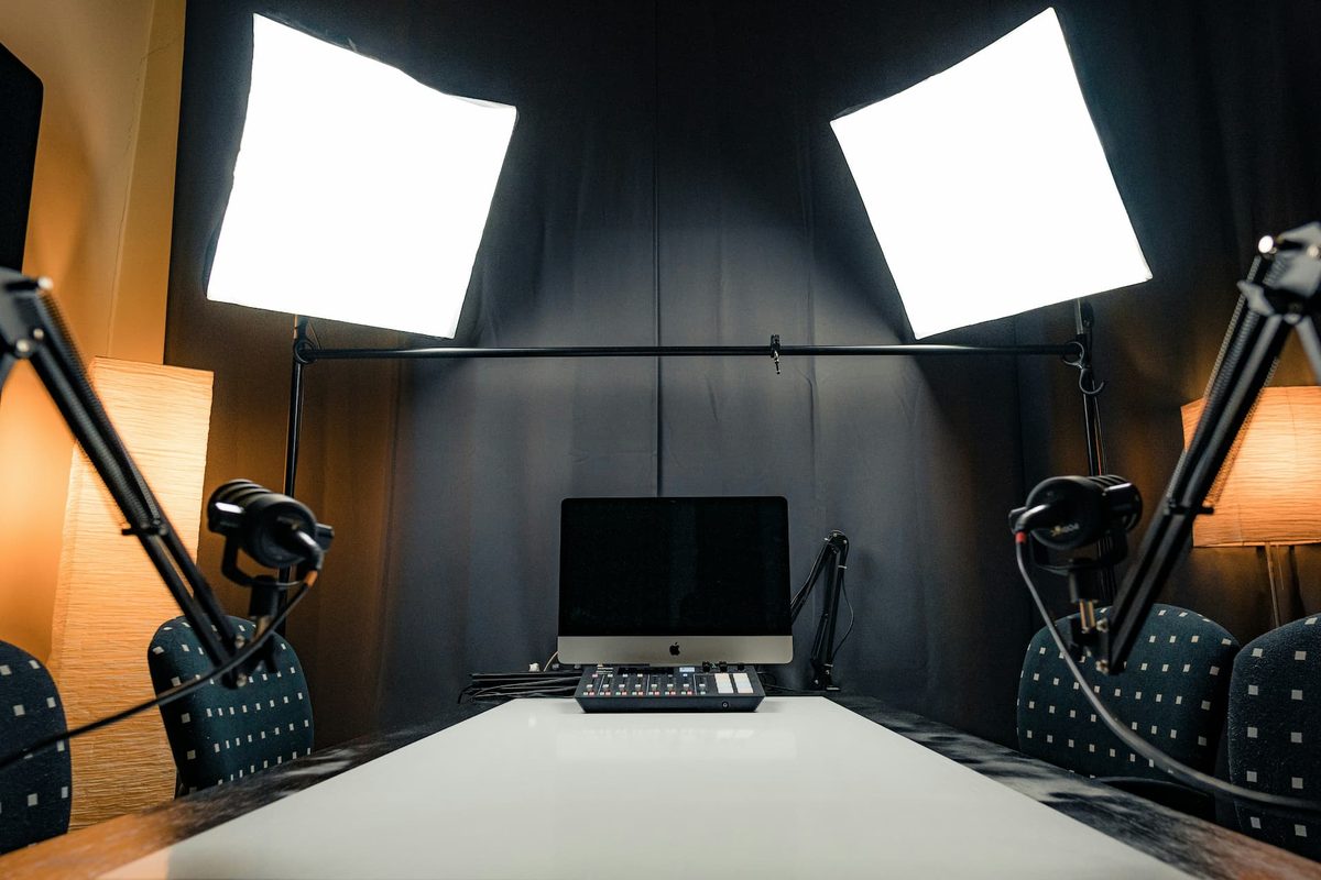 An empty studio with two chairs, a monitor, boom arms, and two softboxes