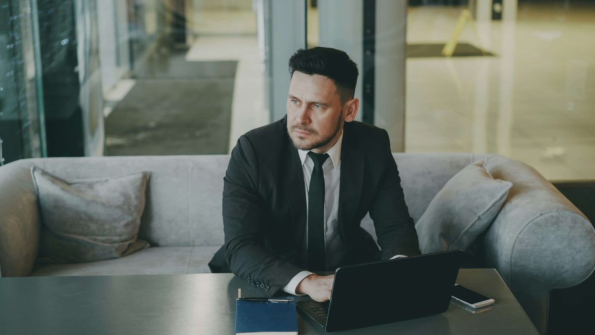 A man in a suit working at a laptop in a lounge