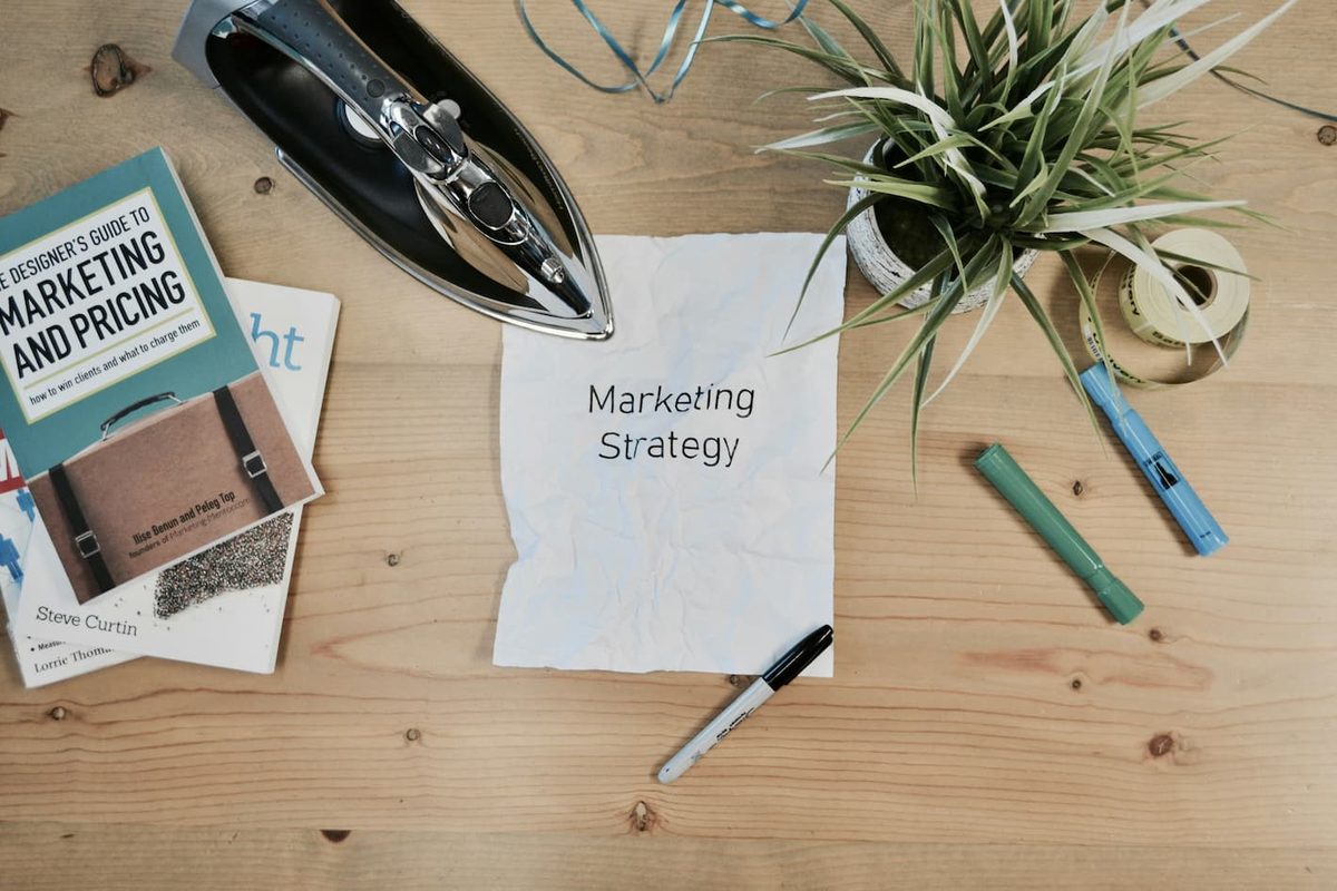 A desk flat lay with a marketing and pricing book and a note reading: marketing strategy